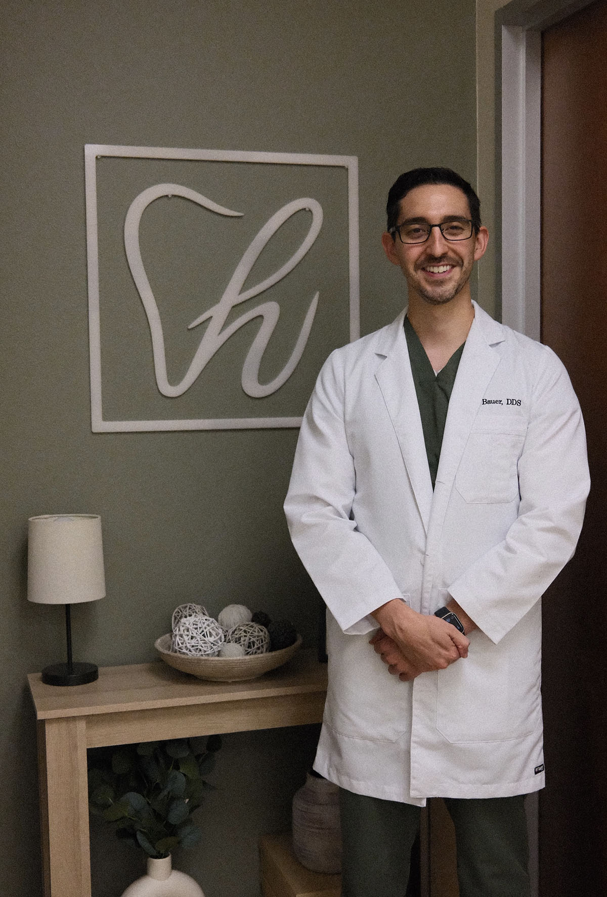 Dr. Travis Bauer standing beside the Hometown Dental Co. logo